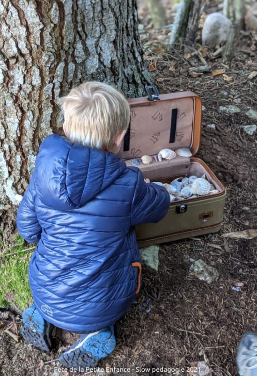 Enfant découvrant une valise de coquillages.