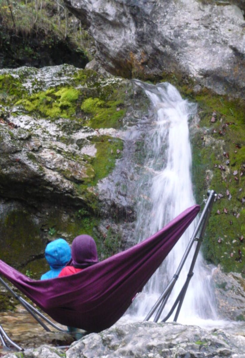 2 personnes dans un hamac devant une cascade.